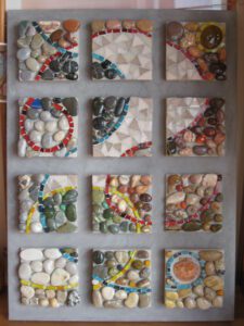 2009 - 06 - Vinca (pâtes de verre, galets, coquillages, et perles sur joint gris ; fond enduit blanc coloré noir)